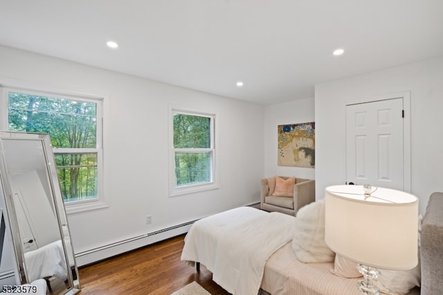 bedroom with hardwood / wood-style flooring, multiple windows, and baseboard heating