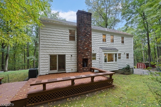 rear view of house with a deck, a lawn, and cooling unit