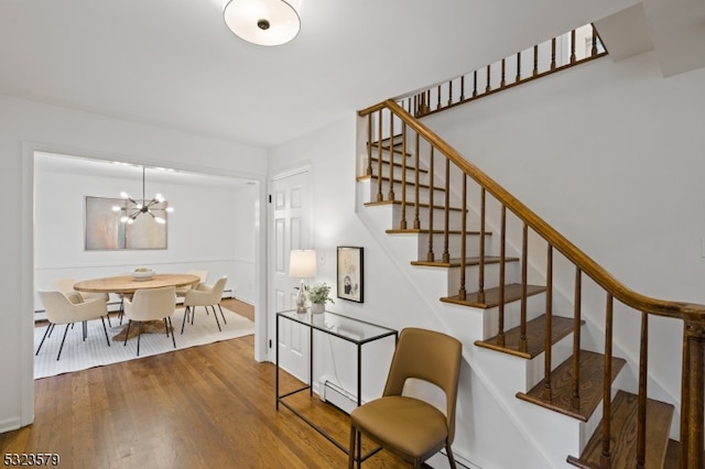 stairs featuring a baseboard radiator, hardwood / wood-style flooring, and an inviting chandelier