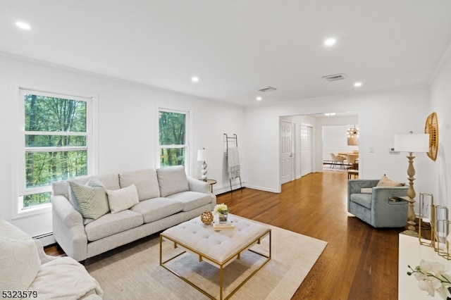 living room featuring a baseboard heating unit, dark hardwood / wood-style flooring, ornamental molding, and a chandelier