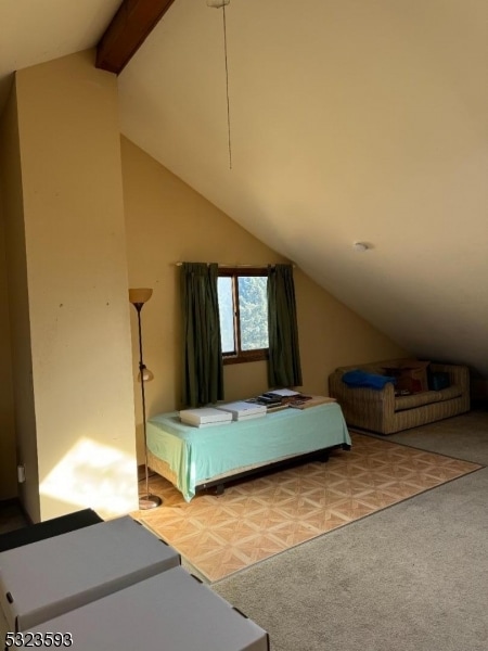 unfurnished bedroom with lofted ceiling with beams and light carpet