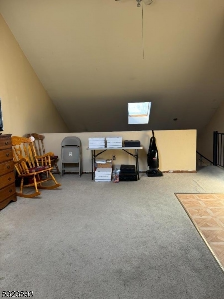 interior space with carpet flooring and vaulted ceiling with skylight