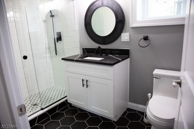 bathroom with tiled shower, vanity, tile patterned floors, and toilet