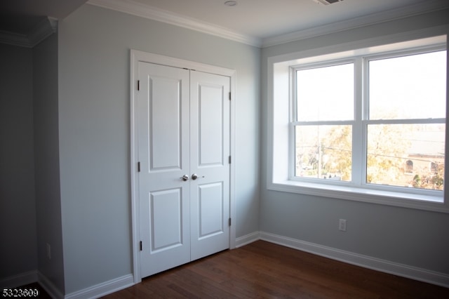 unfurnished bedroom with dark hardwood / wood-style flooring, a closet, and crown molding