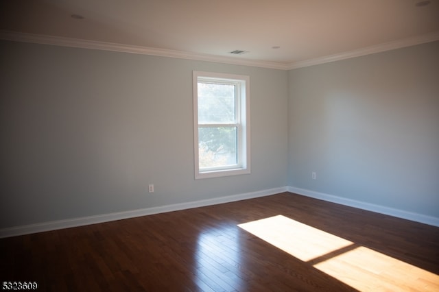 spare room featuring dark hardwood / wood-style flooring and crown molding