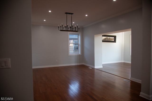 spare room featuring dark hardwood / wood-style floors, an inviting chandelier, and ornamental molding