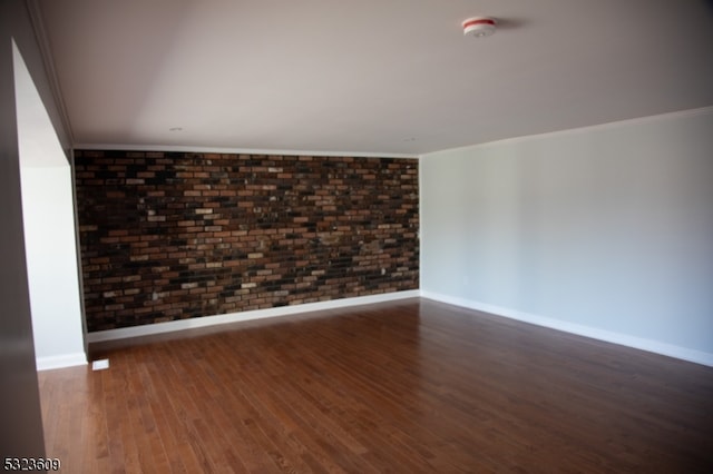 spare room with ornamental molding, brick wall, and dark hardwood / wood-style floors