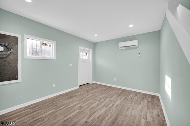 empty room with a wall unit AC, a wealth of natural light, and light wood-type flooring