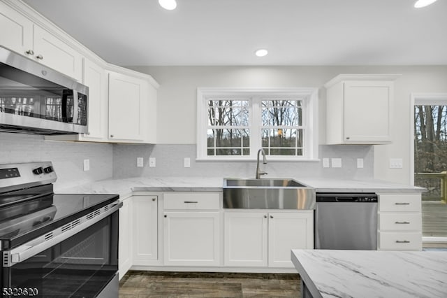 kitchen featuring dark hardwood / wood-style flooring, tasteful backsplash, stainless steel appliances, sink, and white cabinets