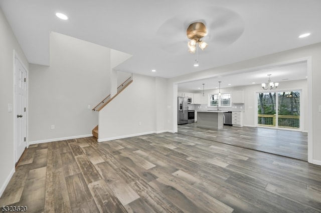 unfurnished living room featuring hardwood / wood-style floors and ceiling fan with notable chandelier