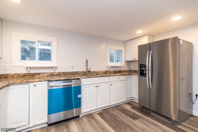 kitchen with stainless steel appliances, dark stone counters, sink, dark hardwood / wood-style floors, and white cabinetry