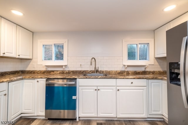 kitchen with dark wood-type flooring, dark stone counters, white cabinets, sink, and appliances with stainless steel finishes