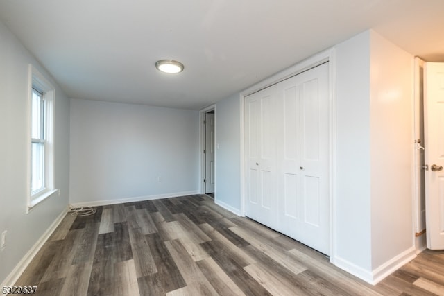 unfurnished bedroom with dark hardwood / wood-style flooring and a closet