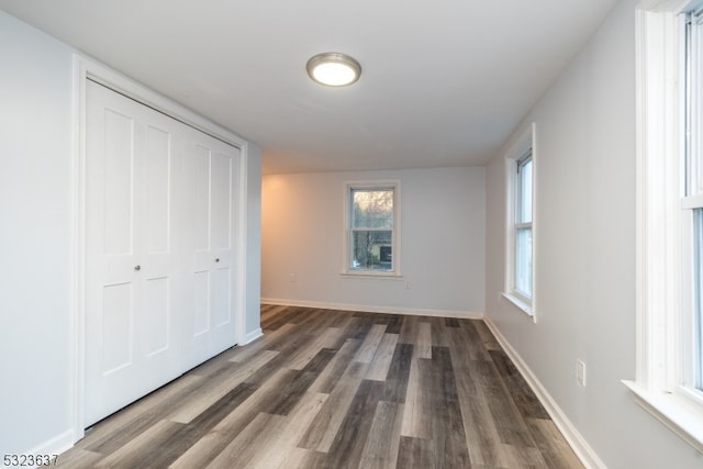 unfurnished bedroom with dark wood-type flooring and a closet