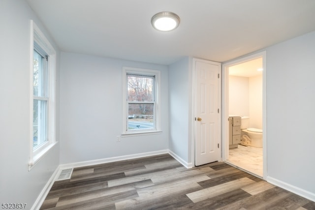 unfurnished bedroom featuring wood-type flooring and connected bathroom