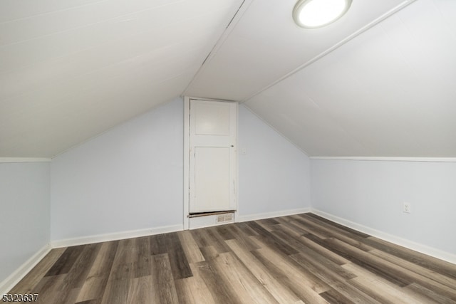 additional living space featuring dark wood-type flooring and lofted ceiling