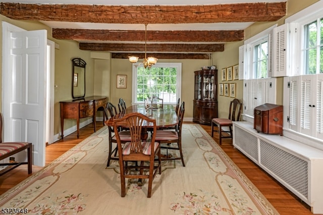 dining space with plenty of natural light, beamed ceiling, hardwood / wood-style floors, and a notable chandelier