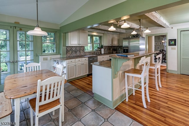 kitchen featuring pendant lighting, backsplash, white cabinets, hardwood / wood-style flooring, and appliances with stainless steel finishes