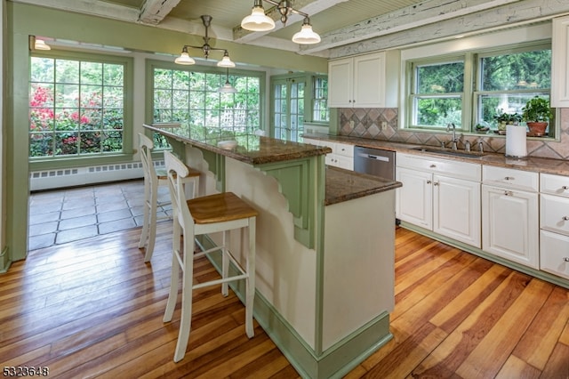 kitchen with a center island, dark stone counters, hanging light fixtures, light hardwood / wood-style floors, and white cabinetry