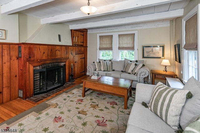 living room featuring hardwood / wood-style floors, beam ceiling, wood walls, and a fireplace