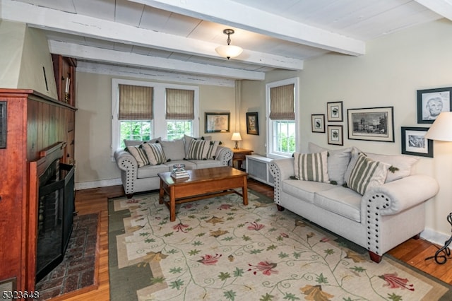 living room with a fireplace, light hardwood / wood-style floors, and beamed ceiling