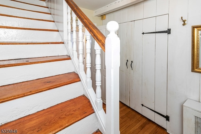 staircase with wooden walls and wood-type flooring