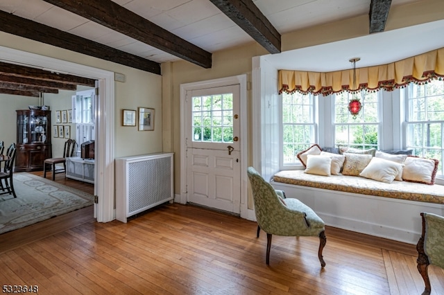 entrance foyer featuring radiator heating unit, beam ceiling, and wood-type flooring