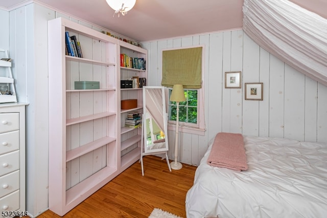 bedroom with hardwood / wood-style floors, wood walls, and lofted ceiling