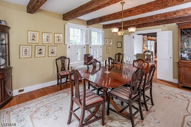 dining area with light hardwood / wood-style flooring, beamed ceiling, and a chandelier