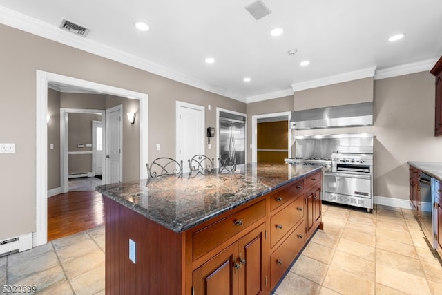 kitchen featuring dark stone countertops, high end stove, crown molding, a kitchen island, and wall chimney range hood