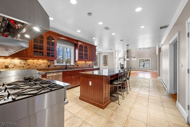 kitchen featuring decorative backsplash, sink, light tile patterned floors, ornamental molding, and a kitchen island