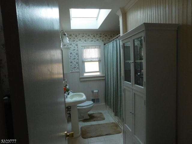 bathroom with a skylight, tile patterned flooring, a shower with curtain, and toilet