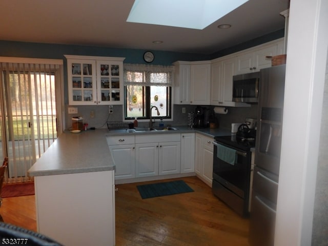 kitchen with white cabinets, sink, a skylight, a wealth of natural light, and stainless steel appliances