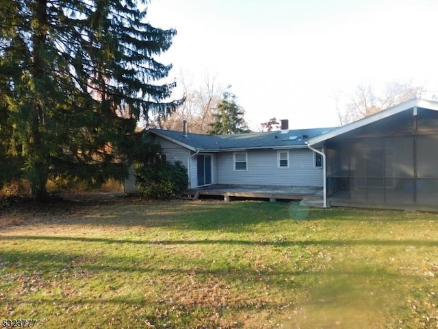 rear view of property featuring a sunroom, a yard, and a deck