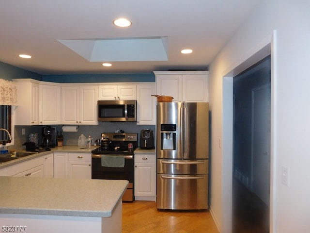 kitchen featuring appliances with stainless steel finishes, a skylight, and white cabinetry