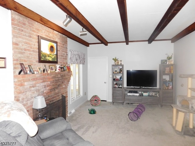 carpeted living room with beam ceiling, rail lighting, and a brick fireplace