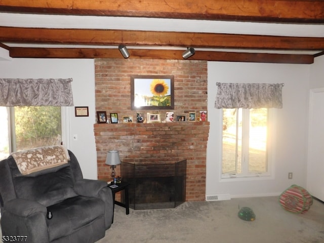 living room featuring beam ceiling, carpet floors, rail lighting, and a brick fireplace