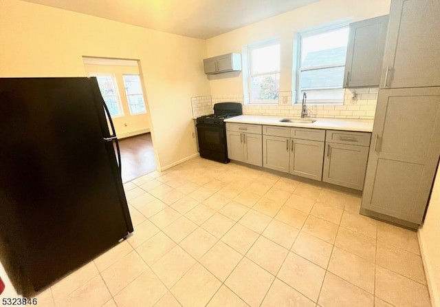 kitchen with black appliances, backsplash, sink, and a wealth of natural light