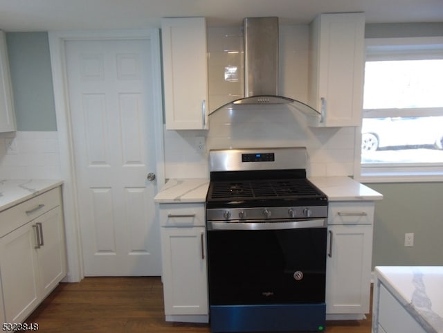 kitchen with wall chimney exhaust hood, stainless steel range with gas cooktop, dark hardwood / wood-style floors, light stone countertops, and white cabinetry