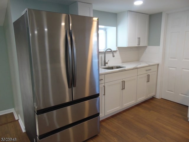 kitchen with sink, tasteful backsplash, dark hardwood / wood-style floors, stainless steel refrigerator, and white cabinetry