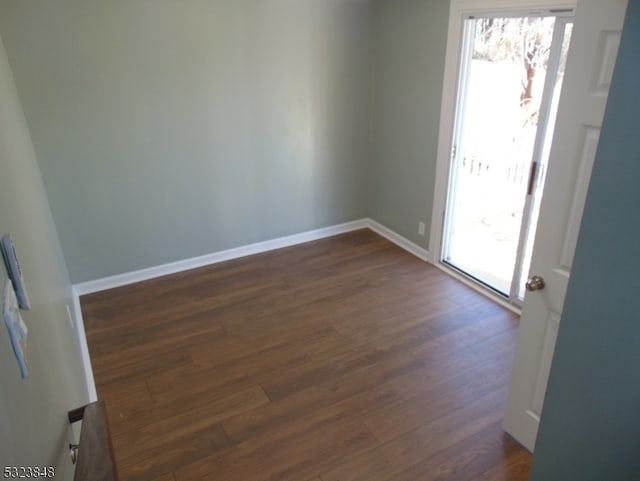 spare room with a wealth of natural light and dark wood-type flooring