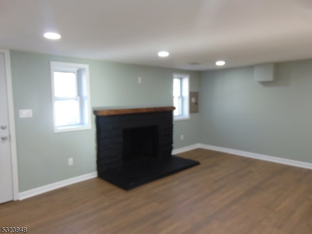 living room with dark hardwood / wood-style flooring, a wealth of natural light, and a brick fireplace