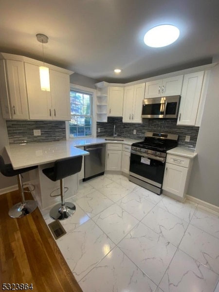 kitchen with sink, tasteful backsplash, pendant lighting, appliances with stainless steel finishes, and white cabinetry