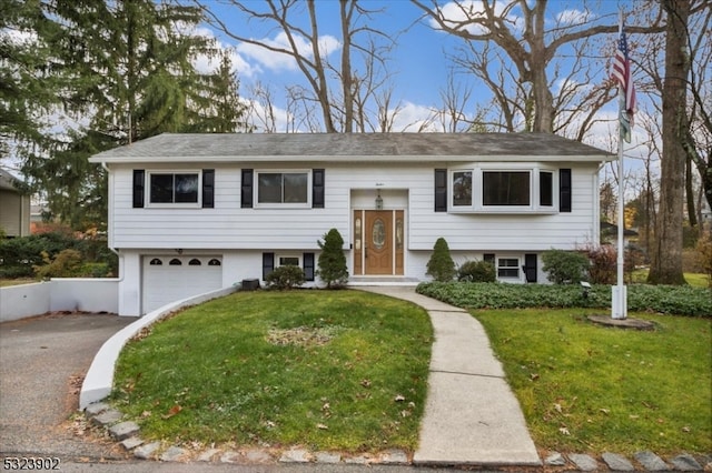 raised ranch featuring a garage and a front yard