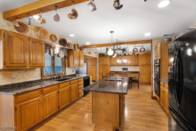 kitchen featuring sink, black appliances, pendant lighting, light hardwood / wood-style flooring, and a kitchen island