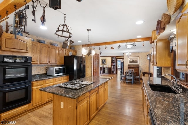 kitchen featuring sink, a center island, dark stone countertops, light hardwood / wood-style floors, and black appliances