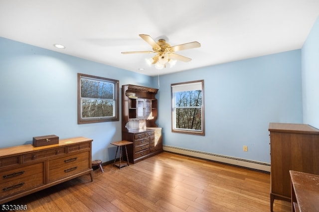 bedroom featuring ceiling fan, light hardwood / wood-style floors, and baseboard heating