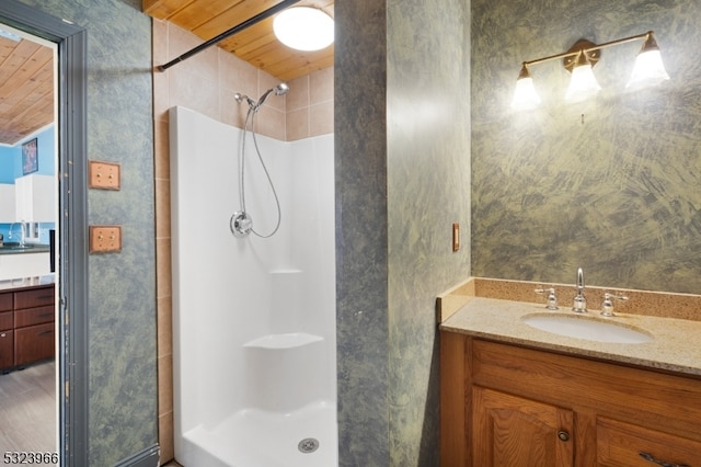 bathroom with a tile shower, vanity, and wood ceiling