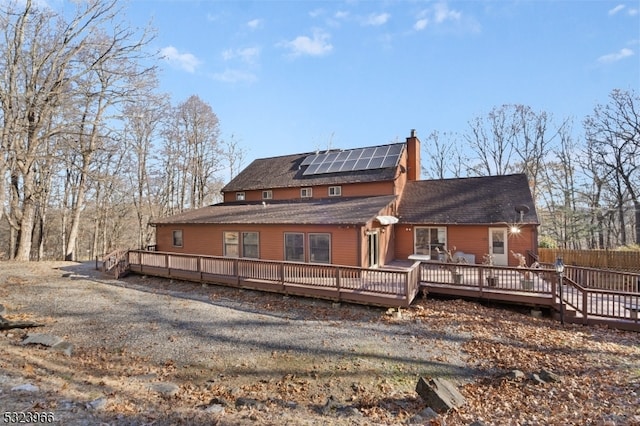 rear view of property featuring solar panels and a deck