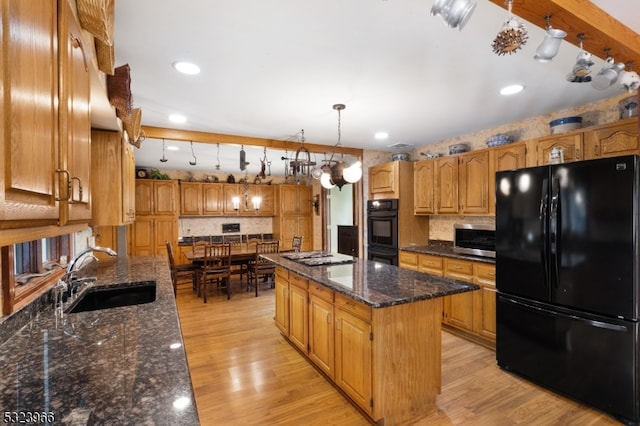 kitchen featuring sink, hanging light fixtures, light hardwood / wood-style flooring, a kitchen island, and black appliances